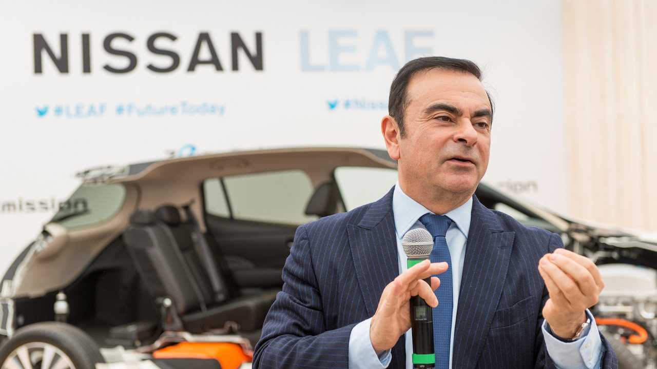 Former Nissan CEO Carlos Ghosn speaking in front of a Nissan Leaf.